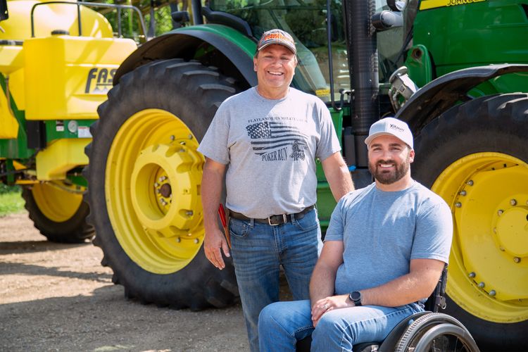 Father and son pose in front of their tractor